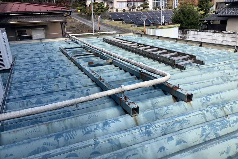 <p>飯田市大休にある株式会社桔梗精機様より、工場屋根塗装工事をご依頼いただきました。<br>

現地調査では、工場屋根全体に紫外線や風雨による色あせや塗膜の劣化が確認されました。また、折板屋根にはサビの発生や防水性能の低下が見られ、このまま放置すると腐食の進行や雨漏りの原因となる恐れがある状態でした。<br>

株式会社横井では、高圧洗浄で長年蓄積した汚れや旧塗膜を丁寧に除去したうえで、防錆下塗りを実施し、高耐候・高耐久なSKプレミアム無機ルーフによる屋根塗装をご提案いたしました。</p><p>* ドローン無料建物診断<br>
* 横井豊文技師 建物診断調査</p><p><br></p>
