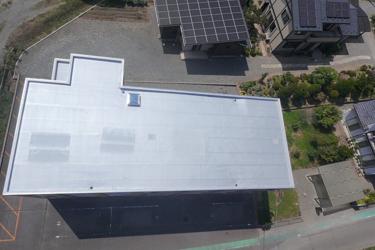 <p>今回の工事では、屋上・階段上・玄関上の既存シート防水を活かし、15MPa以上の高圧洗浄と下地処理を実施した後、ルーフガードNTゴムによるトップコート防水を施工しました。平場・立上り・ドレン周辺まで丁寧に仕上げ、防水性能を回復しています。<br>

共有廊下・階段室では、高圧洗浄後に手摺・笠置・PS点検扉・巾木・階段ササラなどを塗装し、笠置天端コーキングの打ち替えや基礎補修も実施しました。<br>

さらにマンション敷地内では、駐車場および建物周辺のアスファルトひび割れ補修を行い、安全性と美観を改善。建物全体の耐久性・防水性能・景観を総合的に向上させる改修工事となりました。<br>

使用材料・施工内容<br>

屋上・階段上・玄関上防水工事<br>

* 高圧洗浄（15MPa以上）<br>
* 下地処理<br>
* ルーフガードNTゴム トップコート<br>
* 立上りトップコート<br>
* ドレン改修<br>

共有廊下・階段室改修工事<br>

* 高圧洗浄<br>
* 手摺・笠置塗装<br>
* PS点検扉塗装<br>
* 巾木塗装<br>
* 階段ササラ塗装<br>
* 笠置天端コーキング打ち替え<br>
* 基礎補修<br>

舗装補修工事<br>

* 駐車場アスファルトひび割れ補修<br>
* マンション周辺舗装補修<br>

建物診断<br>

* ドローン無料調査<br>
* 横井豊文教師建物診断</p><p><br></p>