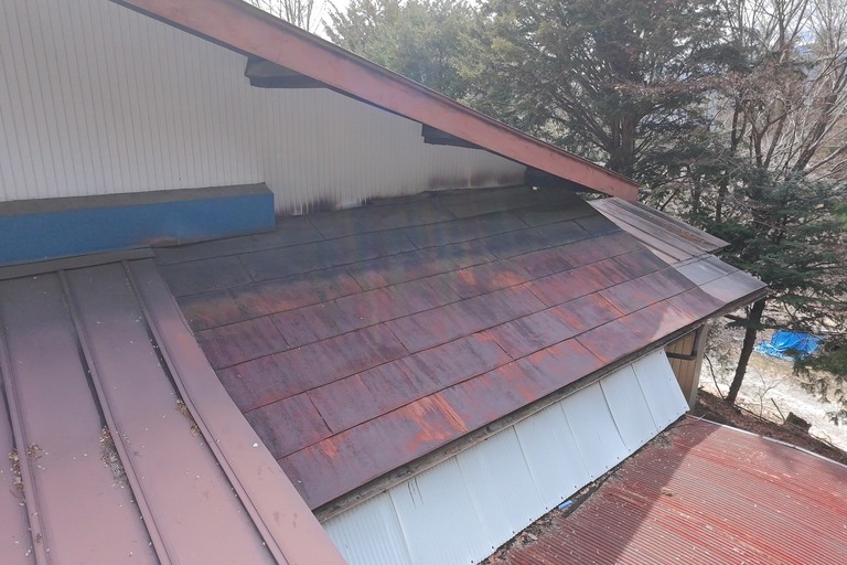 <p>長野県下伊那郡大鹿村にて、ドローンを活用した無料建物診断を実施いたしました。<br>

今回の点検では、屋根全体を空撮し、塗膜の劣化状況やサビの発生、板金部の状態などを詳しく確認しました。<br>

調査の結果、金属屋根全体に塗膜の退色や剥離が広範囲で見られ、素地が露出している箇所も確認されました。また、サビの発生が進行している部分や、防水性能の低下が懸念される箇所も確認されています。一部では過去の補修跡も見受けられましたが、経年劣化が進んでいるため、早めのメンテナンスをご検討いただく時期と判断しました。<br>

株式会社横井では、ドローン無料調査と横井豊史教師建物診断を組み合わせることで、高所まで安全に確認し、建物の状態を写真とともに分かりやすくご報告しております。</p><p><br></p>