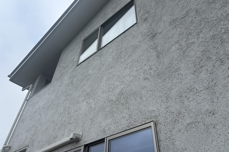 <p>長野県飯田市にて、戸建て住宅のドローンを活用した無料建物診断を実施しました。<br>

今回は、太陽光パネルが設置されている金属屋根を中心に、外壁や雨樋・軒天などの付帯部まで建物全体の状態を確認しました。<br>

屋根をドローンで撮影したところ、金属屋根の表面に広範囲な色あせや塗膜の劣化、黒ずみが確認できました。部分的には黄色～茶色系の変色も見られ、特に太陽光パネルの周辺や屋根下部では劣化が目立っています。<br>

金属屋根は塗膜によって雨水や紫外線から保護されているため、塗膜の劣化を放置するとサビの発生や金属自体の劣化につながる可能性があります。<br>

外壁についても確認したところ、全体的な色あせや汚れに加え、近接調査では表面塗膜の劣化や細かな剥がれ・凹凸部分の傷みが確認できました。<br>

株式会社横井では、ドローン無料調査・横井豊史教師建物診断により、屋根だけでなく外壁や付帯部まで建物全体を確認し、現在の状態に合わせたメンテナンス方法をご提案しています。</p><p><br></p>