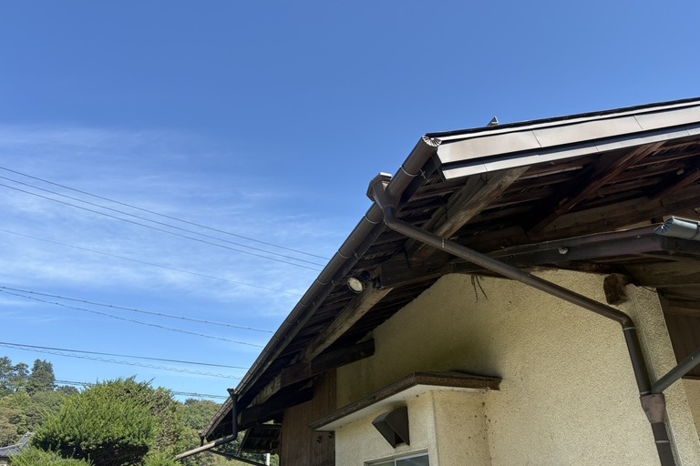 <p>長野県伊那市にて、戸建て住宅のドローンを活用した無料建物診断を実施しました。<br>

今回は、地上からでは状態を確認しにくい屋根や雨樋、軒先などを中心に、ドローン撮影と目視によって建物の状態を確認しました。<br>

主屋の金属屋根は全体として大きな異常は目立ちませんでしたが、別の屋根部分では金属板の塗膜剥がれや色あせ、錆の発生が確認できました。金属部分は塗膜が劣化すると雨水の影響を直接受けやすくなり、錆が進行する可能性があります。<br>

また、雨樋には松葉などの落ち葉やゴミが多く堆積している箇所が確認されました。雨樋の詰まりは雨水が正常に排水されなくなる原因となり、オーバーフローによって軒先や木部を傷める可能性があります。<br>

軒先周辺では木部の経年劣化も見られたため、屋根だけでなく雨樋や木部を含めた定期的な確認が重要な状態です。<br>

株式会社横井では、ドローン無料調査・横井豊文教師建物診断を活用し、普段確認することが難しい屋根や高所部分まで安全に状態を確認しています。</p><p><br></p>