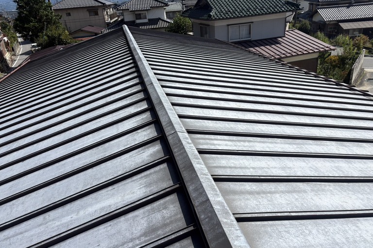 <p>今回のドローン建物診断では、屋根全体を上空から確認することで、地上からでは把握しにくい塗膜の退色・金属素地の露出・赤錆の発生状況を確認することができました。<br>

特に赤錆が広範囲に発生している部分については、今後の腐食進行を防ぐためにも注意が必要です。金属屋根のメンテナンスを行う場合は、錆や劣化した旧塗膜を適切に処理したうえで、錆止めを含めた塗装仕様を検討することが重要となります。<br>

建物診断内容<br>

* ドローン無料調査<br>
* 金属屋根全体の状態確認<br>
* 塗膜の退色・劣化確認<br>
* 赤錆・腐食箇所の確認<br>
* 棟部分の確認<br>
* 谷部・屋根取り合い部分の確認<br>
* 横井豊文教師建物診断</p><p><br></p>