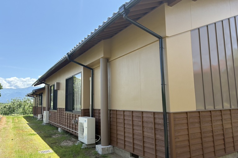 <p>施工では、外壁約245㎡・屋根約32㎡を高圧洗浄し、長年蓄積した汚れや劣化塗膜を丁寧に除去してから塗装を行いました。<br>

外壁はエラスティックフィラーによる下地調整を行い、クラック補修などの部分下地処理を実施したうえで、ユメロック114ラインによる中塗り・上塗りを施工。優れた耐候性・防水性を備えた塗膜により、建物全体の美観と耐久性を向上させました。<br>

屋根は高圧洗浄後、2液サビカットによる下塗り、ハイパーユメロックルーフによる中塗り・上塗りを施工し、防錆性能と耐候性を高めています。<br>

さらに、濡縁・破風板・梁・柱・腰板・軒天・鉄部・水切り・コーキング・雑工塗装など付帯部も丁寧に施工し、建物全体をバランスよく保護しました。<br>

使用材料・施工内容<br>

外壁塗装工事<br>

* 高圧洗浄<br>
* 下塗り：エラスティックフィラー<br>
* 中塗り・上塗り：ユメロック114ライン<br>
* クラック補修・部分下地処理<br>

屋根塗装工事<br>

* 高圧洗浄<br>
* 下塗り：2液サビカット<br>
* 中塗り・上塗り：ハイパーユメロックルーフ<br>

木部塗装<br>

* 濡縁塗装<br>
* 破風板塗装<br>
* 梁・柱塗装<br>
* 腰板・杉ささら子板塗装<br>
* 軒天木部塗装<br>

付帯部塗装<br>

* 壁・軒樋（鉄・塩ビ）<br>
* 水切り（鉄・塩ビ）<br>
* コーキング工事<br>
* 雑工塗装<br>

建物診断<br>

* ドローン無料調査<br>
* 横井豊史教師建物診断</p><p><br></p>